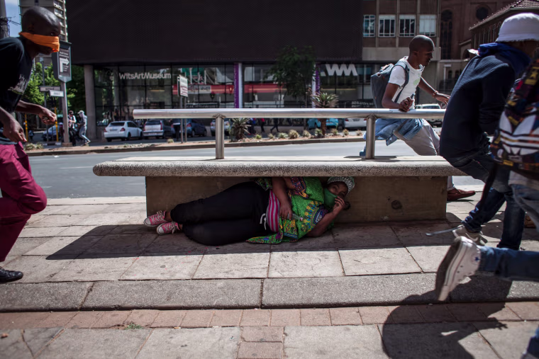 Image: Protesters run and hide as police fire rubber bullets after the FeesMustFall protest spills onto the streets