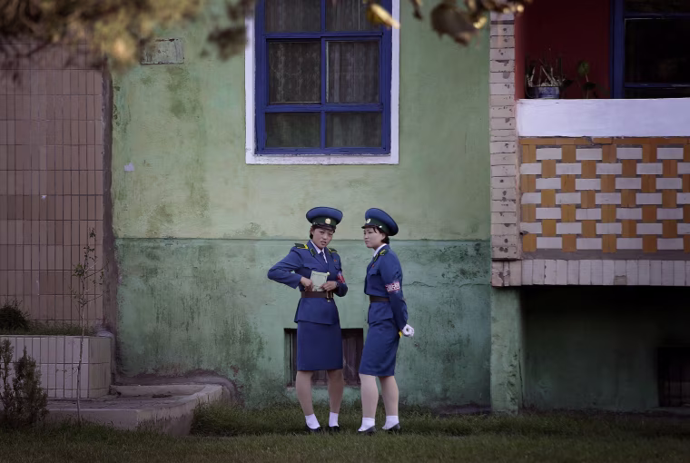Image: North Korean traffic police women chat next to a residential building while off duty