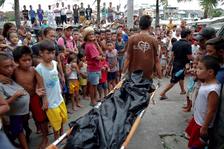 Image: A body is taken out of a house where two men were killed during a drugs related police operation in Manila