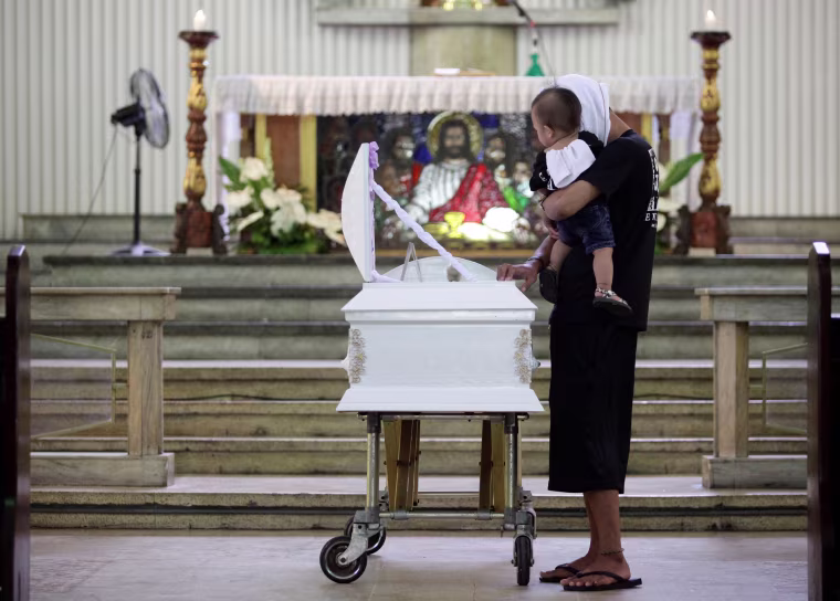 Image: A relative carries the son of Eric Quintinita Sison during burial rites in Pasay city