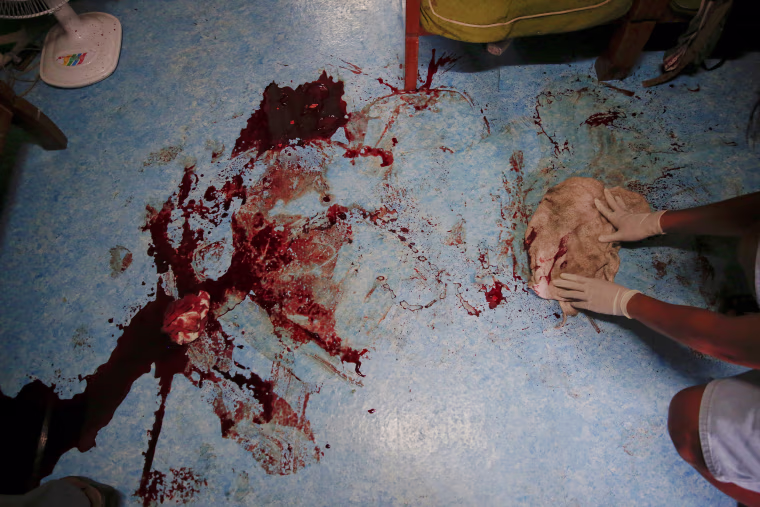 Image: A man cleans blood from the floor inside the house where two person were killed during a drugs related police operation in Manila