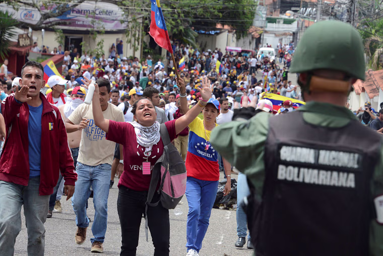 Image: Demonstrators shout slogans in front of Venezuelan National Guard members during a rally demanding a referendum to remove Venezuela's President Maduro in San Cristobal
