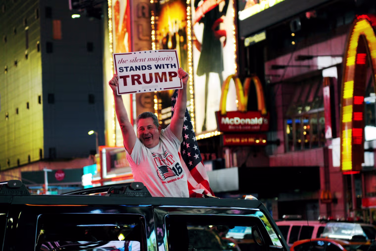 Image: A man leans out of a Hummer shouting words in support of U.S. Republican presidential nominee Donald Trump while driving through Times Square in New York