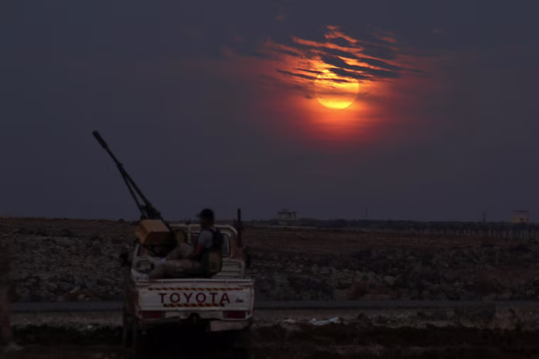 Image: A Free Syrian army fighter sits on a pick-up truck mounted with a weapon, as the supermoon partly covered by clouds is seen in the background, in the west of the rebel-held town of Dael