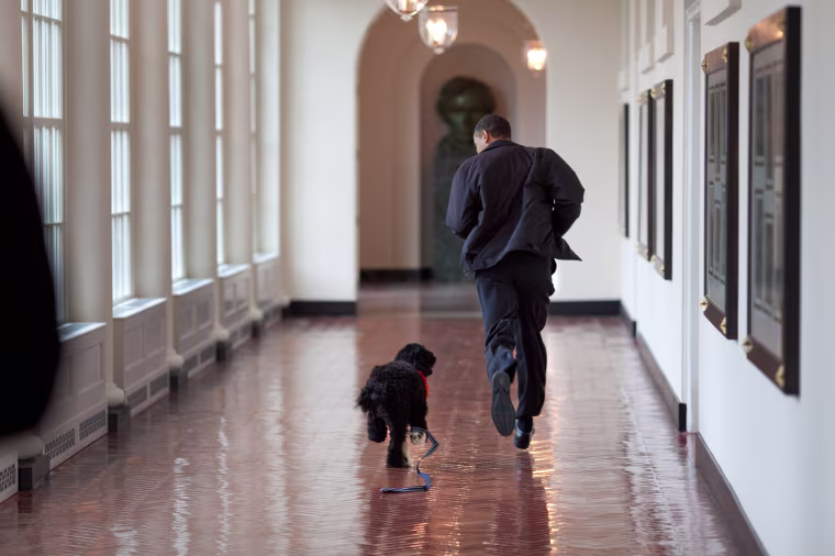 President Barack Obama runs down the East Colonnade with family dog, Bo, March 15, 2009.