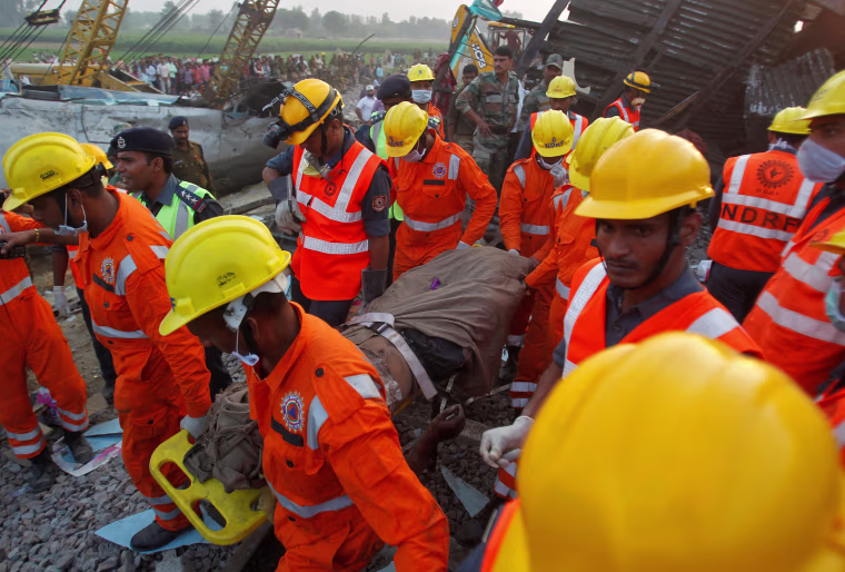 Image: Rescue workers remove the remains of a passenger from the site of a train derailment in Pukhrayan, south of Kanpur city, India