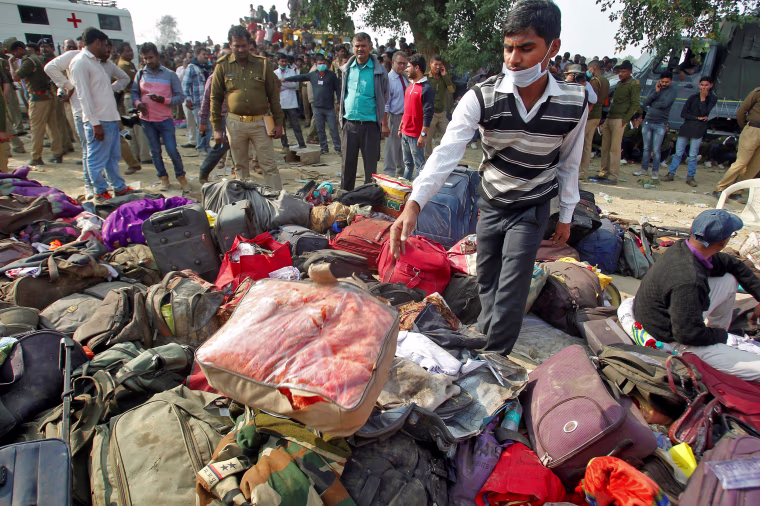 Image: A man sorts through luggage at the site of a train derailment in Pukhrayan, south of Kanpur city, India