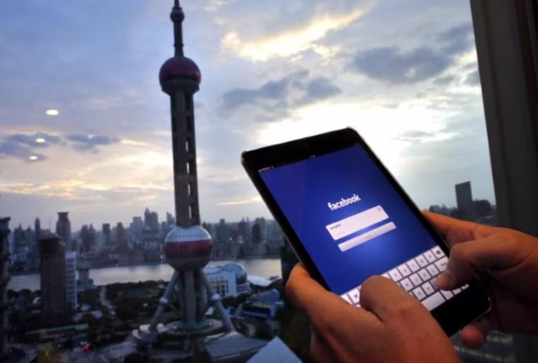 Photo illustration of man holding iPad with a Facebook application in an office building at the Pudong financial district in Shanghai