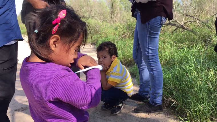 A 3-year-old girl and 5-year-old boy stand at the feet of their mothers, who say they made the long journey to the U.S. from El Salvador.