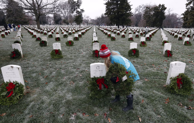 Image: Madeline Espinosa, 11, of Bethesda, Md., places a wreath at a grave as part of Wreaths Across America at Arlington National Cemetery, Dec. 17, in Arlington, Virginia.
