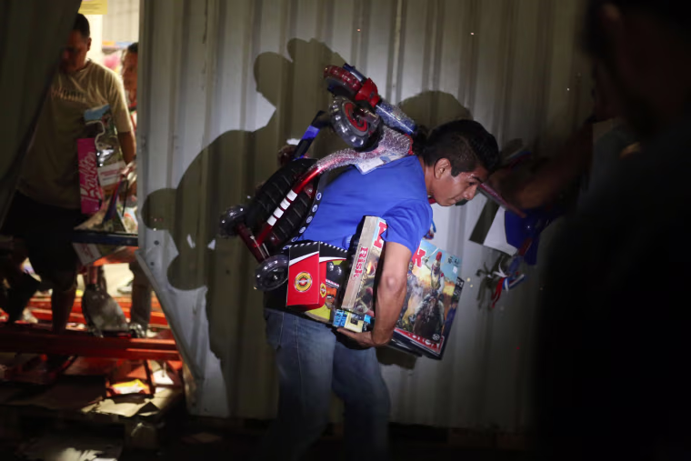 Image: A man runs with toys that was looted from a store during a protest