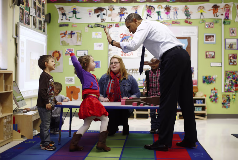 Image: U.S. President Barack Obama high-fives children in a pre-kindergarten classroom at College Heights early childhood learning center in Decatur