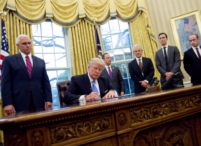 Image: President Donald Trump signs an executive order in the Oval Office of the White House in Washington, D.C., Jan. 23.