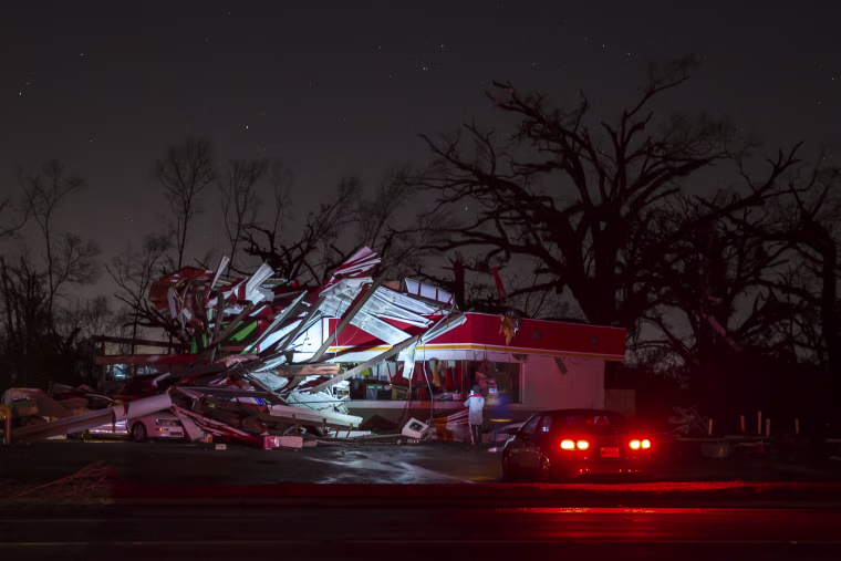 Image: People stop to take a photo of a gas station damaged by an apparent tornado