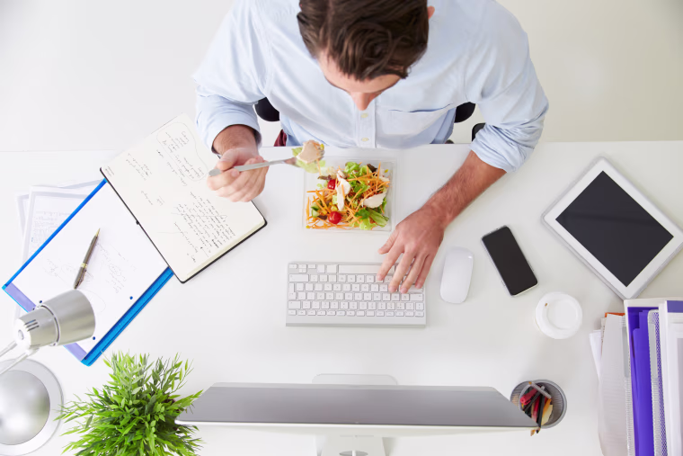 Image: A man eats lunch at his desk