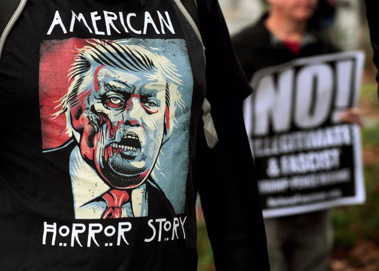 Image: Protesters carry anti-Trump signs during a \"Not My President Day\" demonstration outside City Hall in Los Angeles, California, on Feb. 20, 2017.