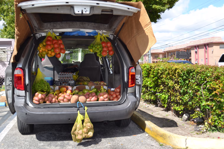 A vendor sells fruits and vegetables from the trunk of a van in the parking lot of a strip mall in Hialeah.