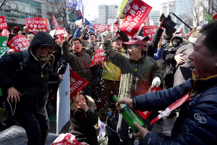 Image: South Koreans celebrate after hearing the Constitutional Court's verdict on March 10, 2017 in Seoul.