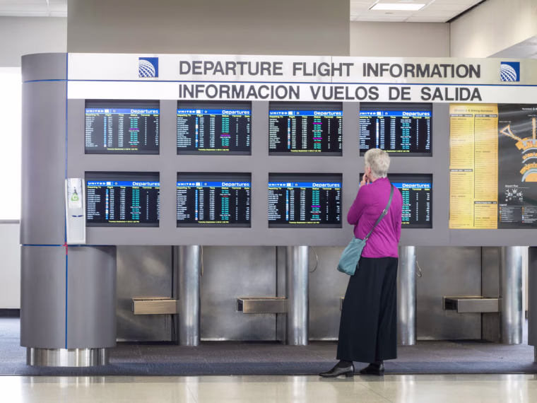 Image: Bilingual Departure Flight Information Board and Passenger, Newark Liberty International Airport, Newark, New Jersey, USA. Image shot 2012.