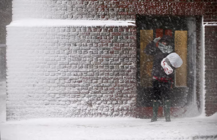 Image: A person stands in the wind-driven snow during a winter storm
