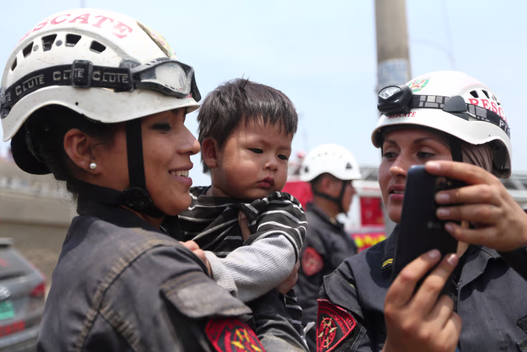 Image: Policewomen calm down a child after the massive landslide and flood, March 17.