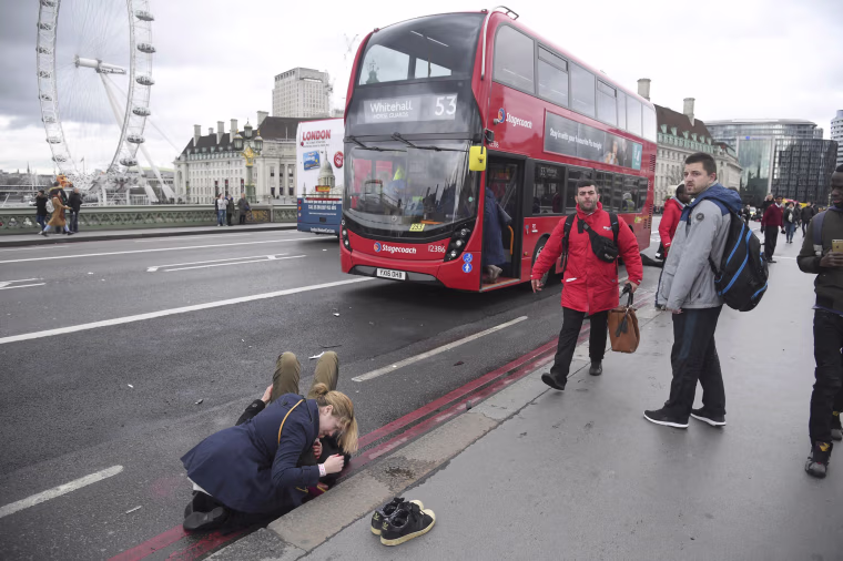 Image: A woman assist an injured person after an incident on Westminster Bridge in London