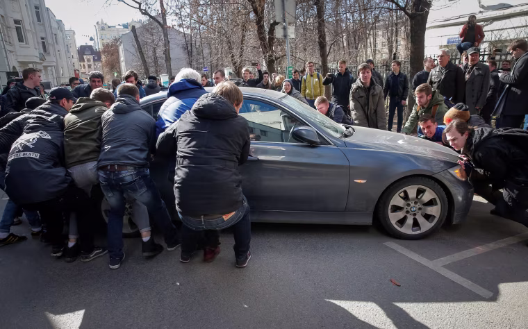 Image: Opposition supporters move a car to block the road to prevent the van transporting detained anti-corruption campaigner and opposition figure Alexei Navalny.