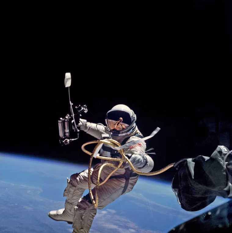 S65-34635 (3 June 1965) --- Astronaut Edward H. White II, pilot on the Gemini-Titan 4 spaceflight, is shown during his egress from the spacecraft. His face is covered by a shaded visor to protect him from the unfiltered rays of the sun. White became the first American astronaut to walk in space. He remained outside the spacecraft for 21 minutes during the third revolution of the Gemini-4 mission. He wears a specially designed spacesuit for the extravehicular activity (EVA). In his right hand, he carries a Hand-Held Self-Maneuvering Unit (HHSMU) with which he controlled his movements while in space. He was attached to the spacecraft by a 25-feet umbilical line and a 23-feet tether line,
