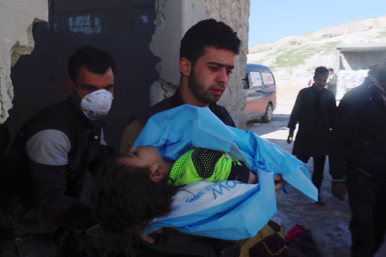 Image: A man carries the body of a dead child, after what rescue workers described as a suspected gas attack in the town of Khan Sheikhoun in rebel-held Idlib