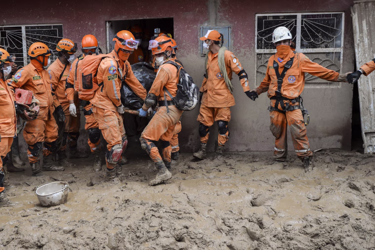 Image: Members of the Colombian civil defense remove the body of a woman who died