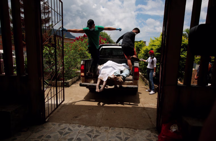Image: Men arrive in a vehicle with bodies to be identified after flooding and mudslides caused by heavy rains in Villagarzon