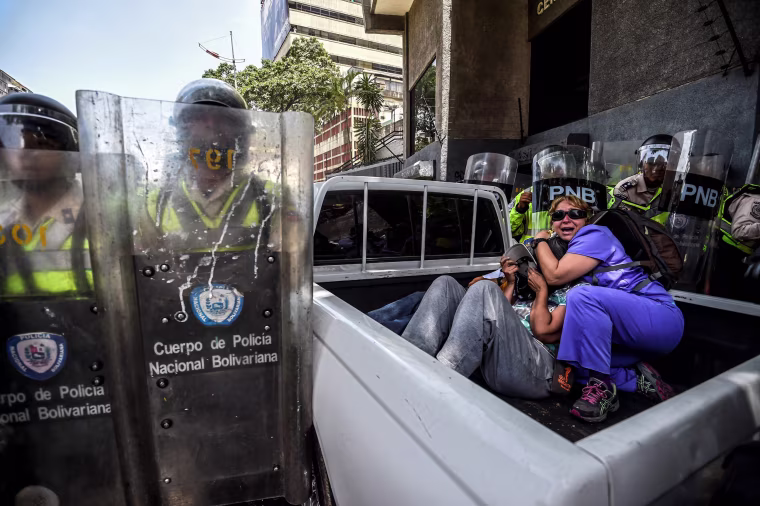 Image: People protect themselves during clashes in Caracas