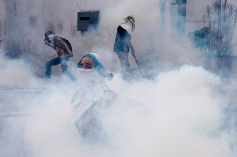Image: Venezuelan opposition activists are are engulfed by a cloud of tear gas during a protest in Venezuela