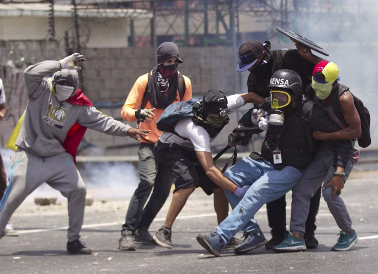 Image: Demonstrators help a journalist who was injured in a leg while covering the opposition rally Venezuela