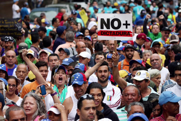 Image: Demonstrators carrying a sign that reads \"No more dictatorship\" rally in Venezuela