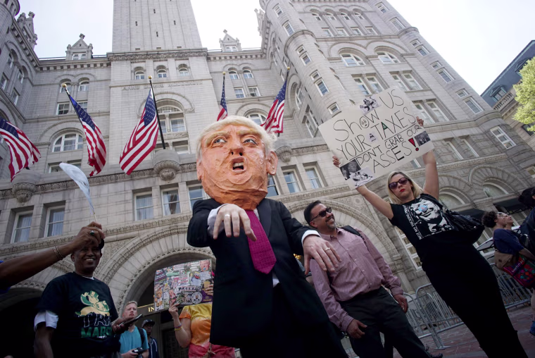 Image: Protesters walk by the Trump hotel during the Tax March in Washington, DC.