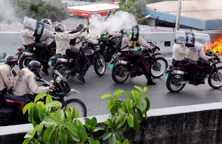 Image: Riot police fire tear gas toward opposition supporters during clashes in Caracas