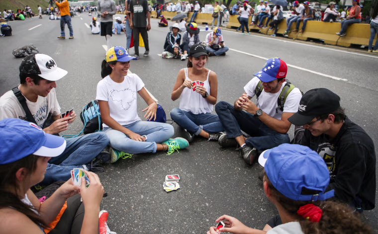 Image: A group of people play cards during a sit-in in Caracas