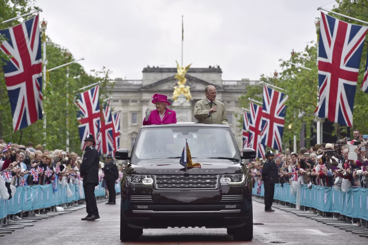 Image: Britain's Queen Elizabeth and Prince Philip wave to guests attending the Patron's Lunch on the Mall, an event to mark her 90th birthday, in London