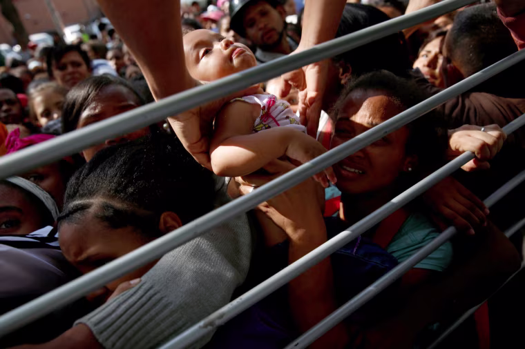 Image: A baby is lifted out of a crowd while her mother waits on the street with others who are trying to buy diapers outside a pharmacy in Caracas, Venezuela March 18, 2017.