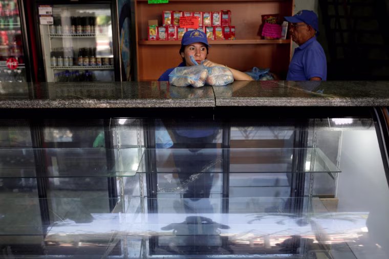 Image: A saleswoman holds bags of bread as she waits for customers at a bakery in Caracas, Venezuela, March 17, 2017.