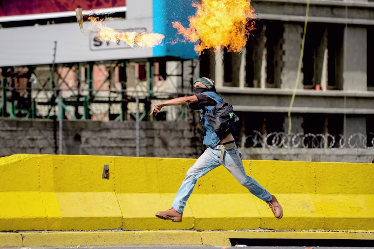 Image: An opposition activist throws a Molotov cocktail at the police during clashes on May Day, in Caracas on May 1, 2017.