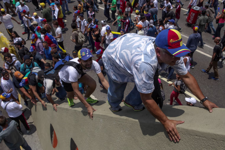 Image: Hundreds of people protest while some climb a bridge in Caracas, Venezuela, on April 10, 2017.