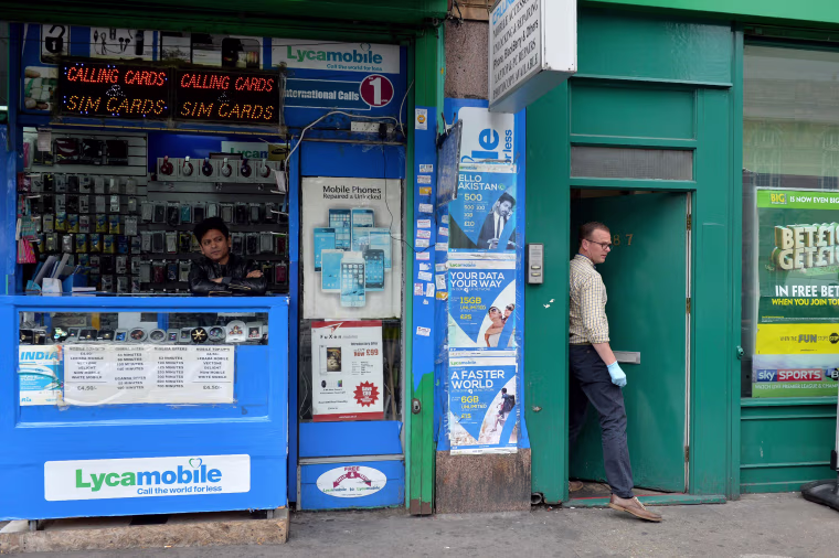 Image: A man stands in a shop as a police officer exits the door of a property in East Ham, in east London on June 4, 2017, following a raid as police continue their investigations following the June 3 terror attacks in central London.