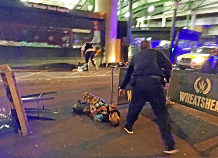 Image: A suspected terrorist, wearing what appear to be canisters around his waist, is on the ground after being knocked down by police officers in Borough Market, late last night. He was shot and killed by police officers.