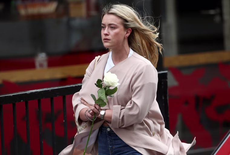 Image: A woman cries as she carries a tribute to leave on the London Bridge.
