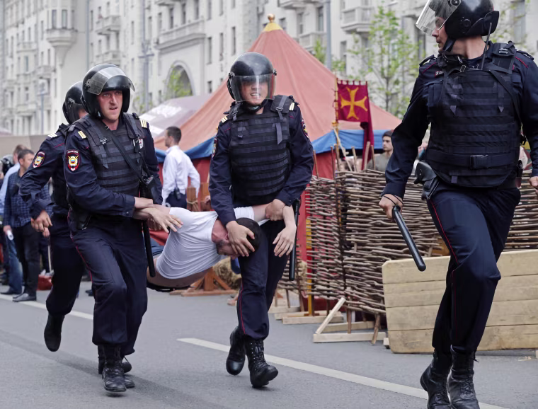 Image: Russian police officers carry a detained participant of an unauthorized opposition rally