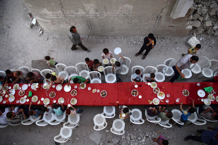 Image: People break their fast amidst damaged buildings during an Iftar in the rebel held besieged Douma neighbourhood of Damascus