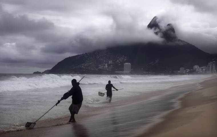 Image: A man sifts through sand for valuable buried items