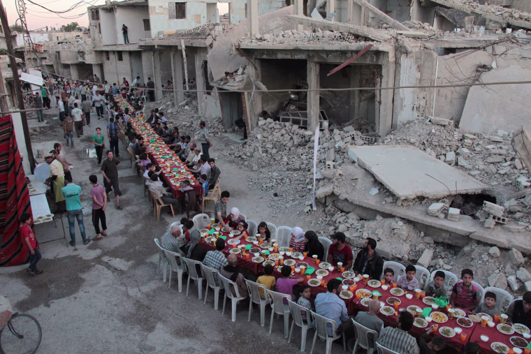 Image: Syrians share a meal on a war-torn street